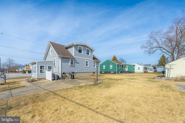 rear view of property with a patio area, a lawn, roof with shingles, and fence