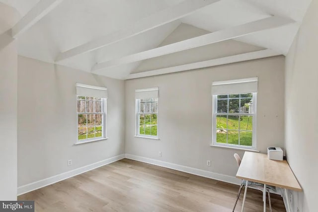 unfurnished office featuring lofted ceiling with beams, baseboards, a wealth of natural light, and wood finished floors