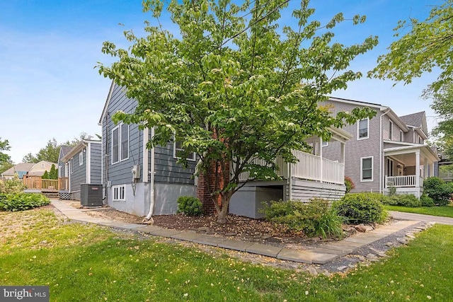 view of side of property featuring cooling unit, a lawn, and a wooden deck