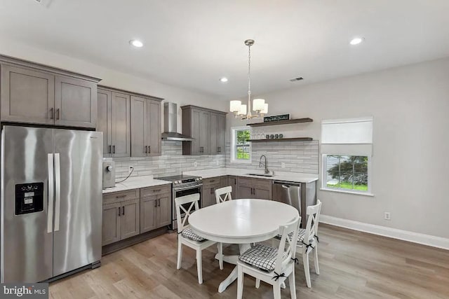 kitchen with open shelves, appliances with stainless steel finishes, wall chimney range hood, a notable chandelier, and tasteful backsplash