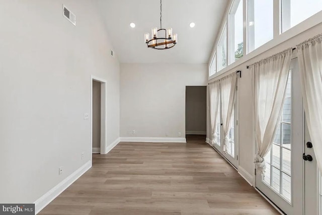 interior space with a notable chandelier, visible vents, high vaulted ceiling, and baseboards