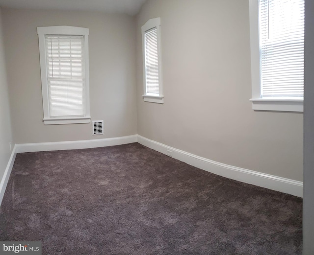 unfurnished room with a wealth of natural light, visible vents, baseboards, and carpet