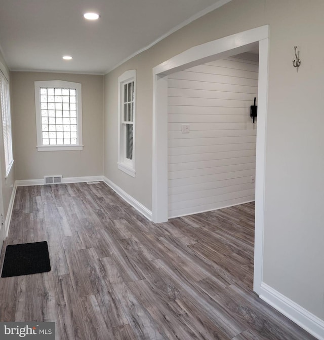 empty room featuring visible vents, baseboards, wood finished floors, and ornamental molding