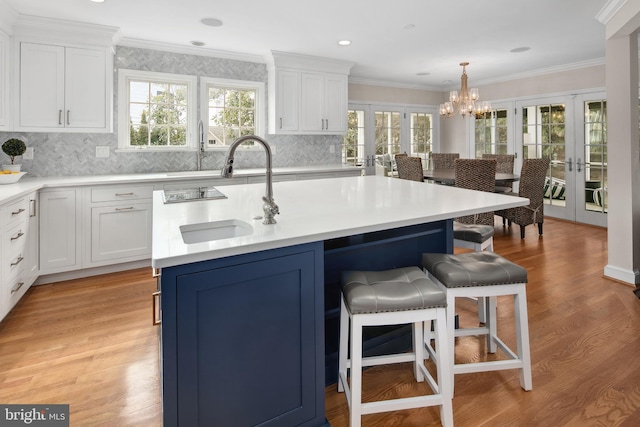 kitchen featuring white cabinets, french doors, a breakfast bar, and a sink