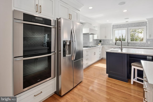 kitchen with a sink, stainless steel appliances, ornamental molding, and light countertops