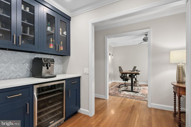 bar featuring beverage cooler, light wood finished floors, ornamental molding, decorative backsplash, and a dry bar