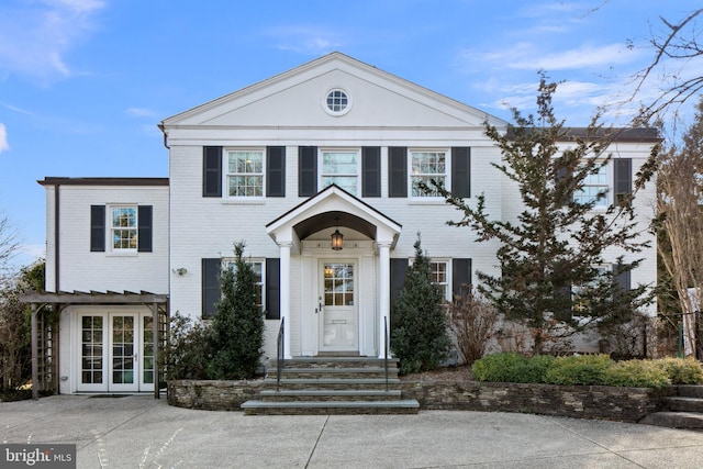 neoclassical home featuring brick siding