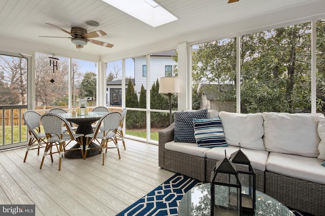 sunroom / solarium with a healthy amount of sunlight, a skylight, and a ceiling fan