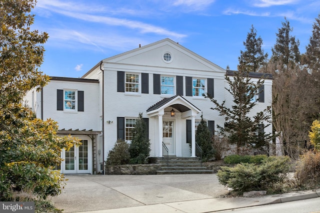 neoclassical home with french doors and brick siding