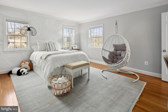 bedroom with ornamental molding, baseboards, and wood finished floors