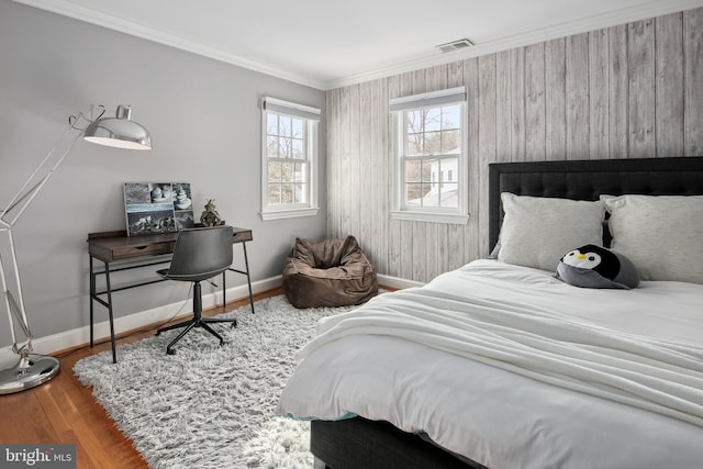 bedroom with visible vents, crown molding, baseboards, and wood finished floors