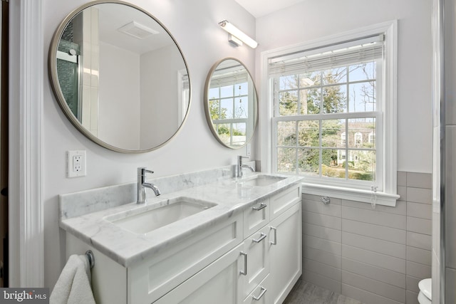 full bath with tile walls, a wealth of natural light, and a sink