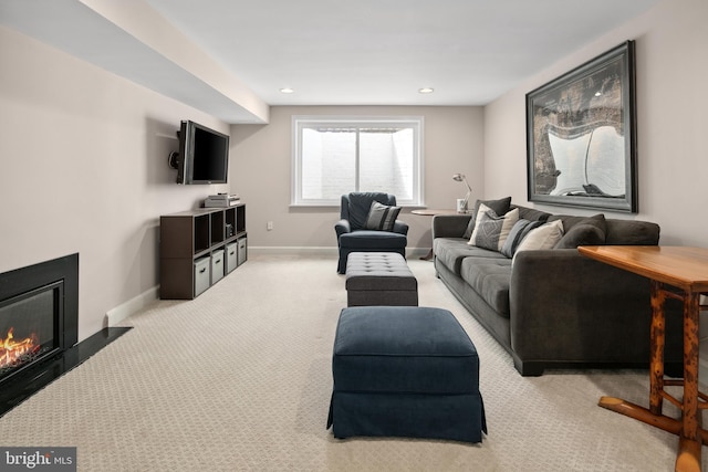 living area featuring light carpet, a glass covered fireplace, recessed lighting, and baseboards