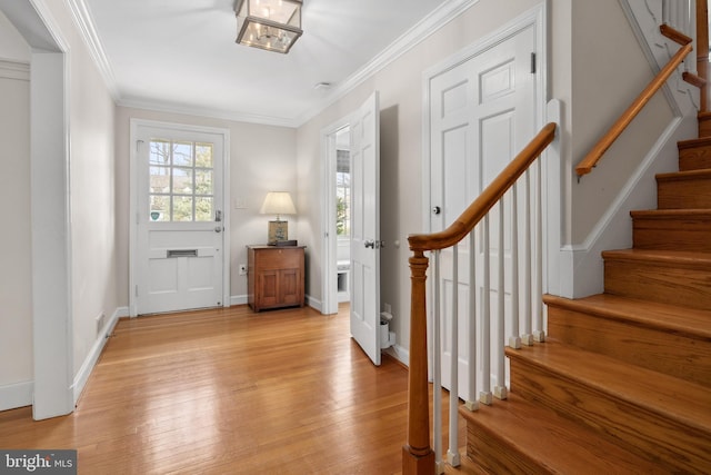 entrance foyer with light wood-style flooring, stairs, baseboards, and ornamental molding