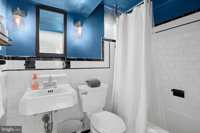 bathroom featuring shower / bath combo with shower curtain, toilet, tile walls, and a sink