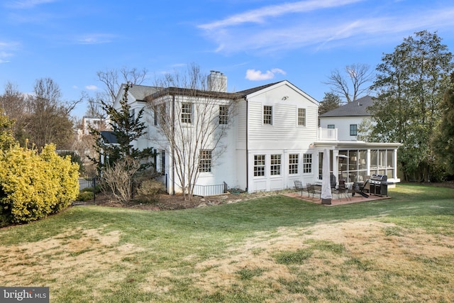 back of property featuring a yard, a patio, a chimney, and a sunroom