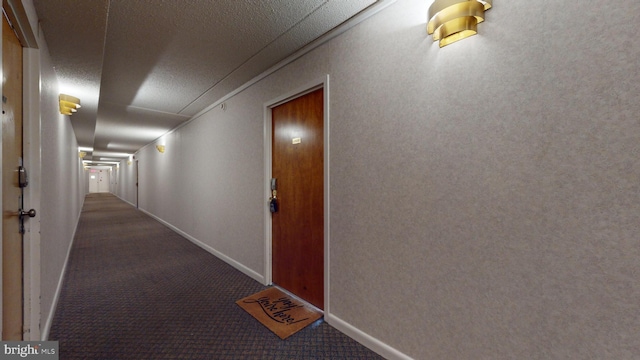 hallway with baseboards, a textured ceiling, and carpet flooring