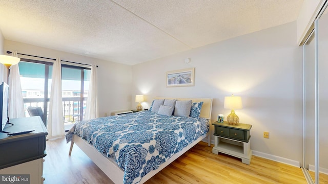 bedroom featuring a closet, baseboards, a textured ceiling, and wood finished floors