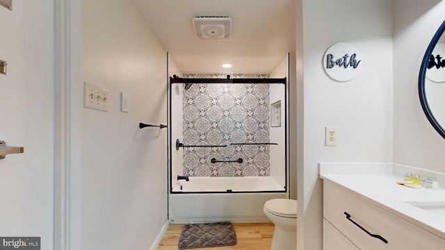 full bathroom featuring shower / bath combination with glass door, toilet, wood finished floors, and vanity