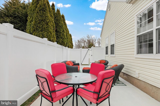 view of patio with outdoor dining area, a fenced backyard, and a gate