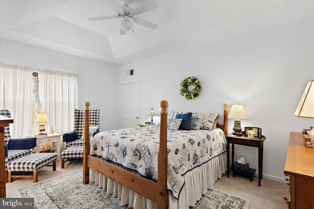 bedroom featuring visible vents, baseboards, a tray ceiling, light carpet, and a ceiling fan