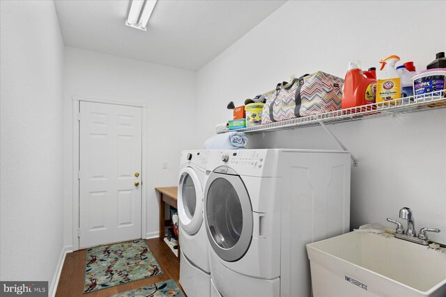 laundry room featuring washing machine and clothes dryer, laundry area, wood finished floors, and a sink