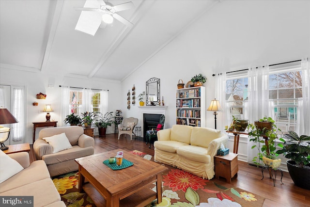 living room featuring beamed ceiling, a fireplace, wood finished floors, high vaulted ceiling, and a ceiling fan