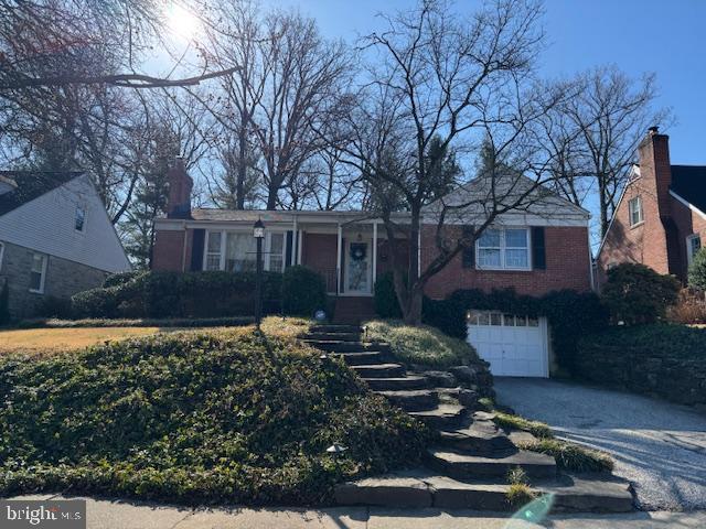 view of front of house with an attached garage, brick siding, and driveway