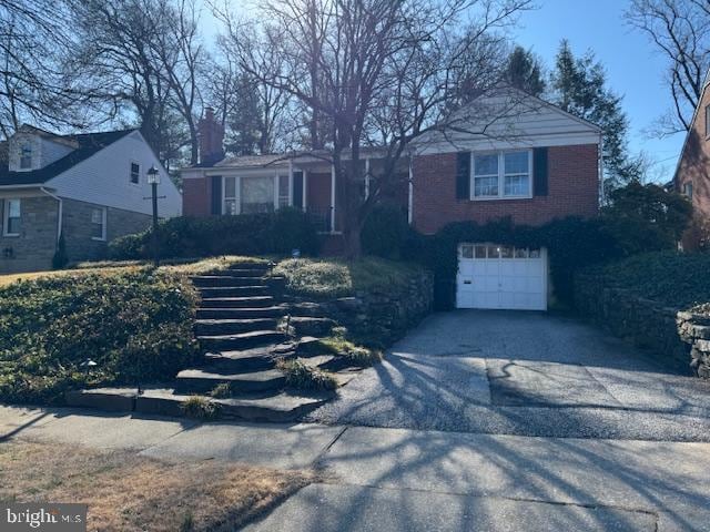 view of front facade featuring aphalt driveway, brick siding, and a garage