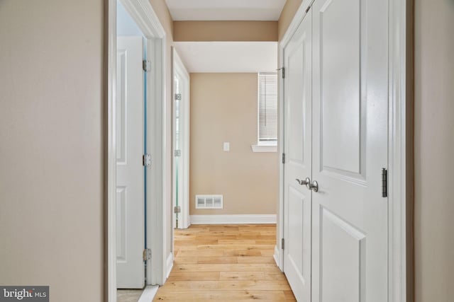 hallway with visible vents, baseboards, and light wood-style floors