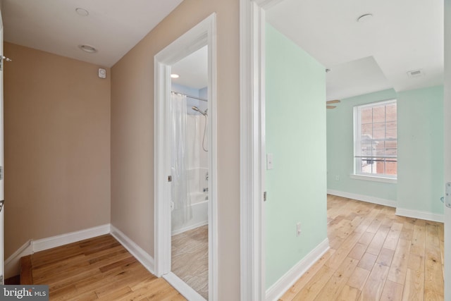 hall with baseboards and light wood-style floors