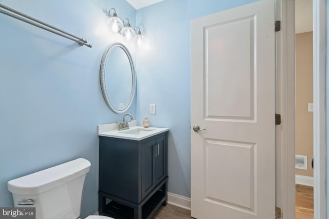 bathroom with visible vents, toilet, vanity, and baseboards