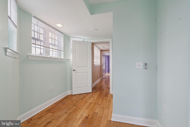 corridor featuring light wood-style floors and baseboards