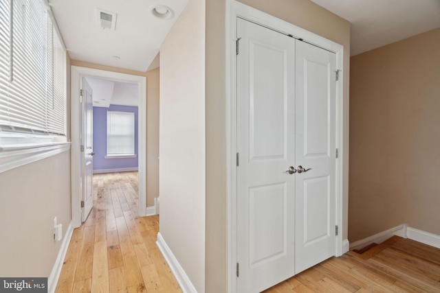 corridor with visible vents, baseboards, and light wood-style flooring