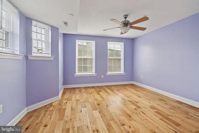 unfurnished room with hardwood / wood-style floors, baseboards, visible vents, and a ceiling fan