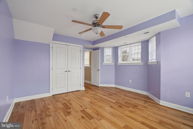 unfurnished bedroom with visible vents, a closet, light wood finished floors, baseboards, and ceiling fan