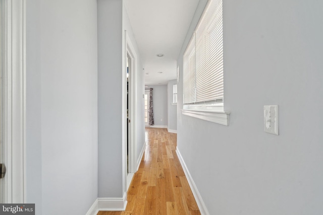 corridor with baseboards and light wood-style floors