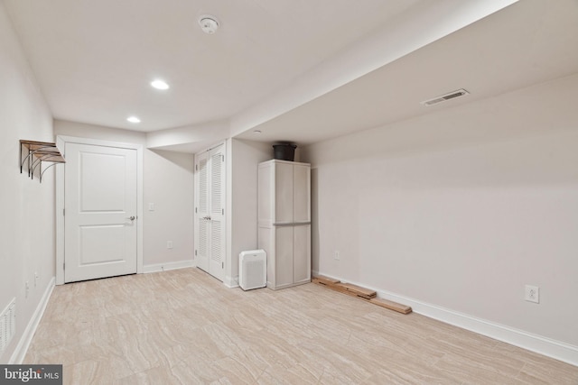 finished below grade area featuring light wood-style flooring, recessed lighting, baseboards, and visible vents