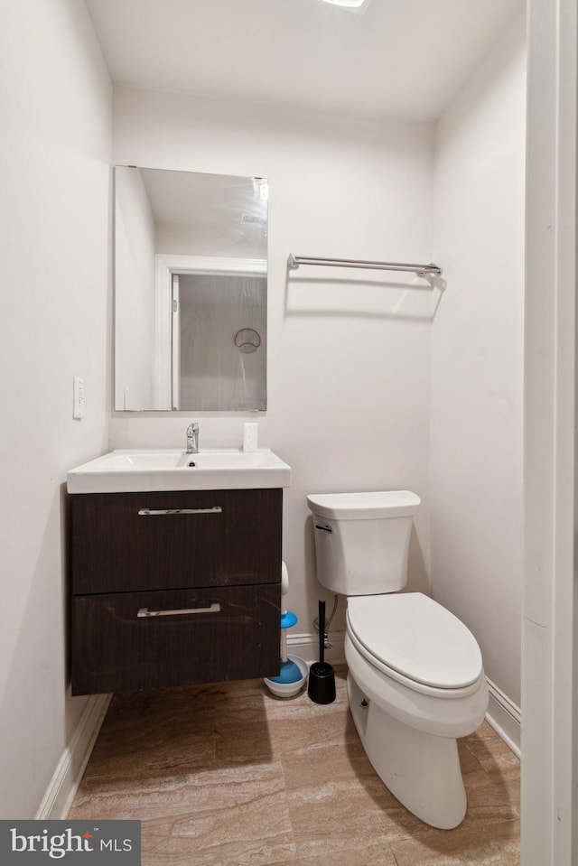 half bath with vanity, toilet, wood finished floors, and baseboards