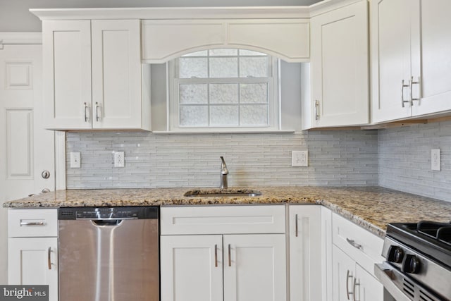 kitchen with a sink, tasteful backsplash, appliances with stainless steel finishes, white cabinets, and light stone countertops