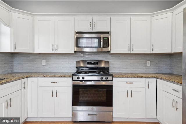 kitchen featuring stainless steel appliances, white cabinets, and decorative backsplash