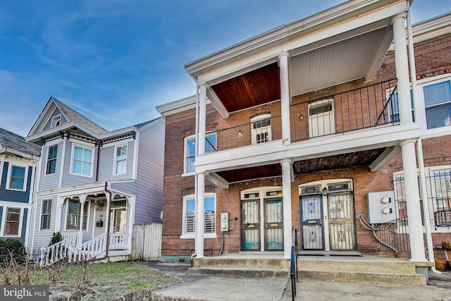 view of property featuring a balcony and brick siding