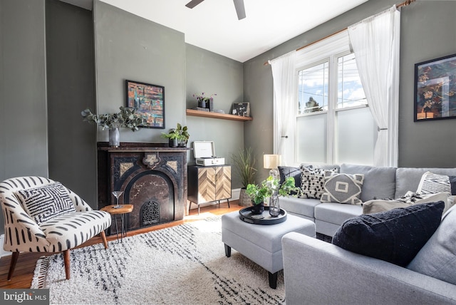 living room featuring a fireplace, ceiling fan, and wood finished floors