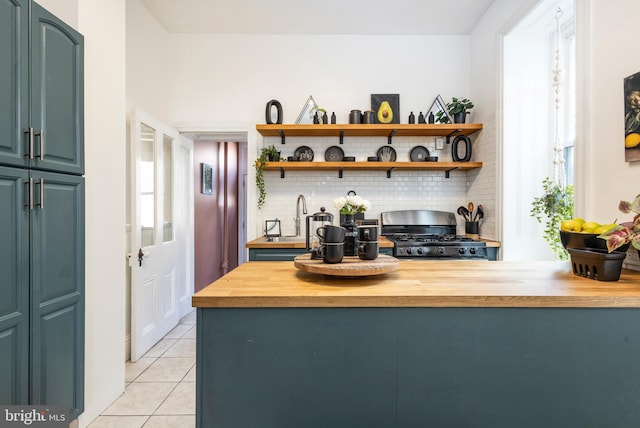 interior space featuring backsplash, a healthy amount of sunlight, light tile patterned flooring, gas stove, and wood counters