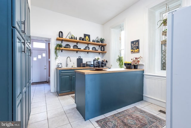 bar with light tile patterned floors, a healthy amount of sunlight, backsplash, and a sink