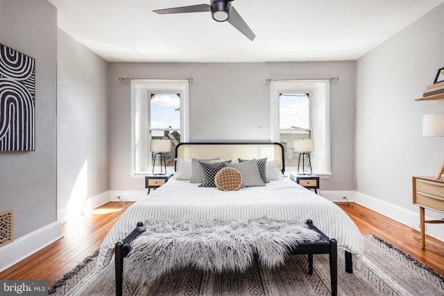 bedroom with baseboards, multiple windows, and wood finished floors