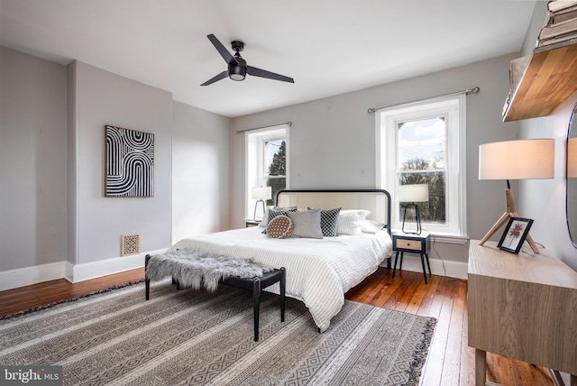 bedroom with multiple windows, a ceiling fan, baseboards, and wood-type flooring