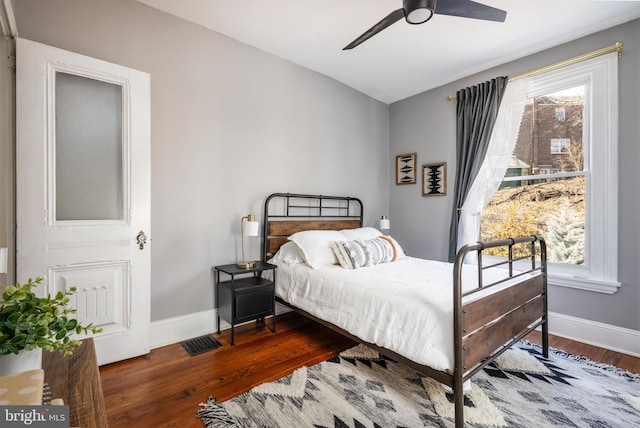 bedroom with visible vents, multiple windows, wood finished floors, and baseboards