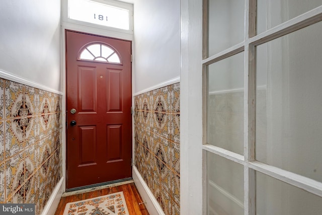 foyer with tile walls, wood finished floors, and a wainscoted wall