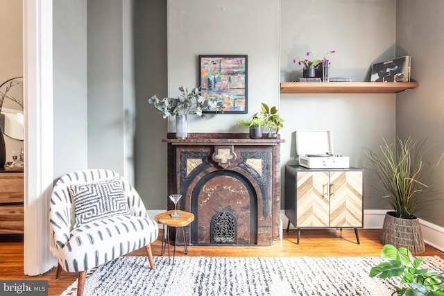 sitting room with baseboards, wood finished floors, and a fireplace